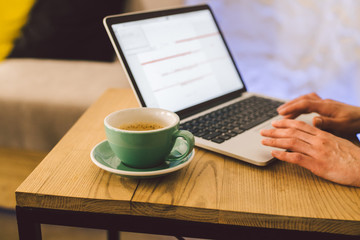 Closeup business woman hands using laptop with cup coffee. Woman Hands Typing keyboard computer In Coffee Shop. smartphone and hot cup Cappuccino in table. People lifestyles concept. Freelance theme