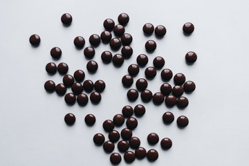 Pile of scattered chocolate dragee on white background