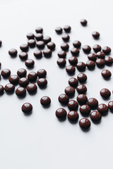 Pile of scattered chocolate dragee on white background