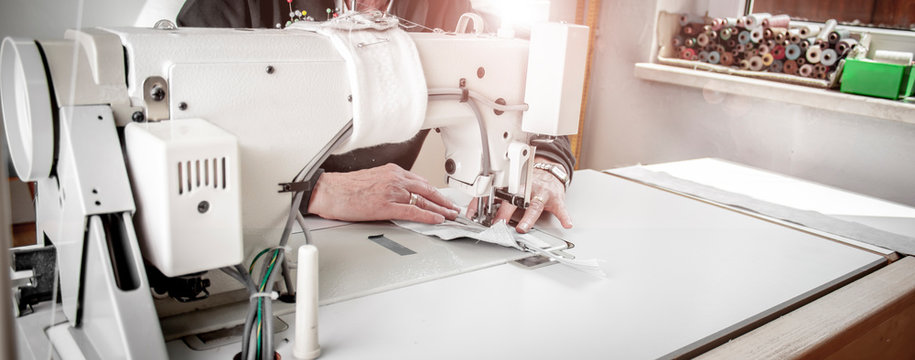 professionelle Näherin näht mit Inustrienähmaschine einen Kissenbezug aus Stoff