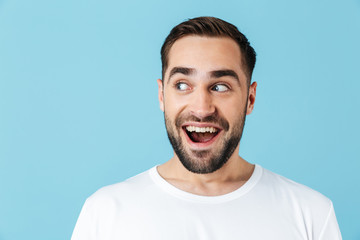 Obraz premium Excited young dreaming bearded man posing isolated over blue wall background looking aside.