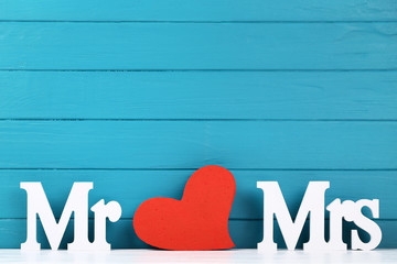 White letters Mr and Mrs with red heart on blue wooden background