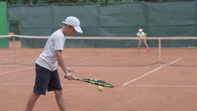 tennis match, sports player child boy with contestant hitting racket on ball pass through net to each other at court during tournament