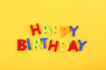 Text Happy Birthday by plastic letters on yellow background