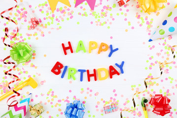Text Happy Birthday by plastic letters with decorations and confetti on white background