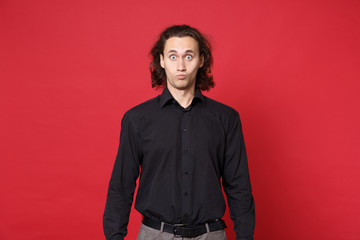 Fototapeta premium Przystojny zszokowany stylowy młody kręcone długie włosy mężczyzna w czarnej koszuli pozowanie na białym tle na czerwonym tle portret studio. Ludzie koncepcja stylu życia szczere emocje. Makieta miejsca na kopię. Patrząc na aparat.