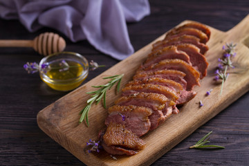 Sliced duck breast, lavender honey and rosemary on serving board