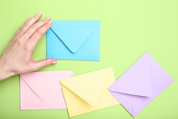 Female hand with colorful paper envelopes on green background