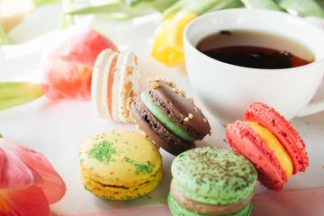 Cup of tea, delicious macaroon and bright tulips, sweet dessert