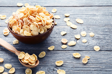 Corn flakes in bowl with spoon on grey wooden table