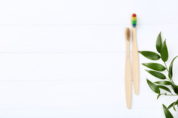 Bamboo toothbrushes with green leafs on wooden table