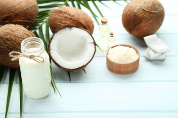 Coconut milk in bottle with oil and palm leafs on wooden table