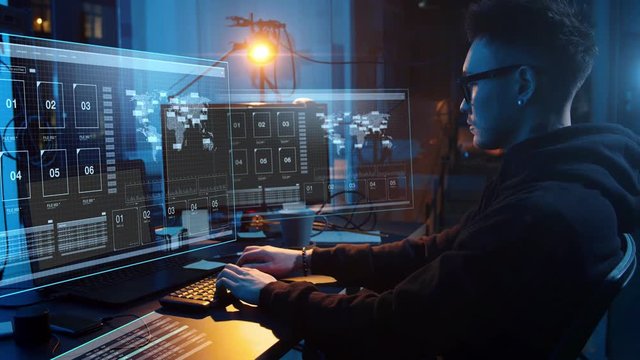 cybercrime, hacking and technology concept - asian male hacker in dark room writing code or using computer virus program for cyber attack