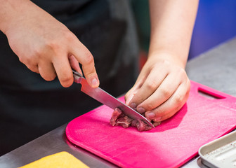 chef cutting beef meat, cutting raw meat on board in kitchen