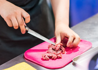 chef cutting beef meat, cutting raw meat on board in kitchen