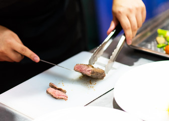 chef with knife and cutting tasty grilled steak, Chef preparing meal in the kitchen