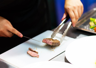 chef with knife and cutting tasty grilled steak, Chef preparing meal in the kitchen