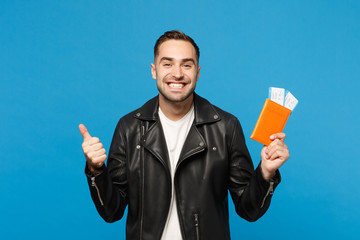 Young happy unshaven man in black jacket white t-shirt hold in hand passport tickets isolated on blue wall background. Passenger traveling abroad getaway. Air flight journey concept Mock up copy space