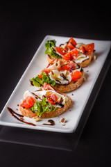 Bruschetta with tomatoes, lettuce, camambert, balsamic vinegar
