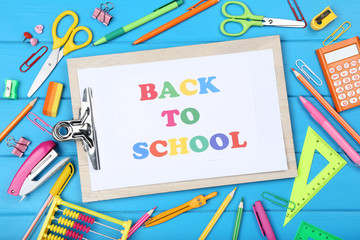 Text Back To School on clipboard with stationery on blue wooden table