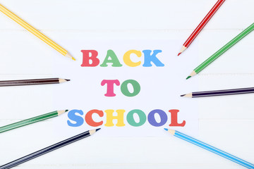 Text Back To School with colorful pencils on white wooden table
