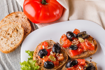 Italian bruschetta with tomato, black olives, lettuce and mustard