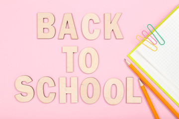Text Back To School with notepad and pencils on pink background