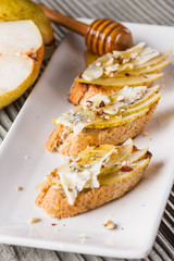 Appetizer bruschetta with pear, honey, walnut and blue cheese on white plate