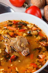 Georgian soup. Kharcho with rice, tomato, beef, garlic and herbs in bowl on wooden table