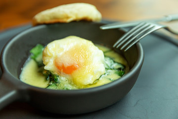 Fried eggs in a small cast-iron portion pan on the table. Healthy beautifully decorated breakfast in the cafe. Close-up.