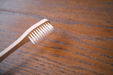 Close up of wooden bamboo toothbrush on wood table with copy space, sustainable lifestyle, zero waste concept