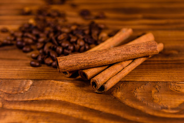 Pile of the coffee beans and cinnamon sticks on wooden table