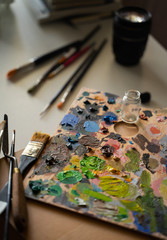 Art studio with a palette full of different colors of oil paint in a table