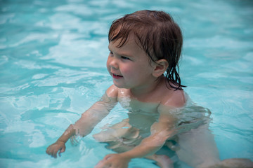 3 years old girl playing swimming at the blue pool