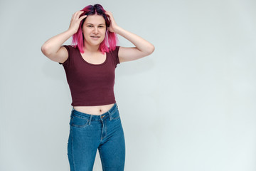 Full-length portrait of a young pretty teenager girl in jeans and a vest with beautiful purple hair on a white background in the studio. Talking, smiling, showing hands with emotions.