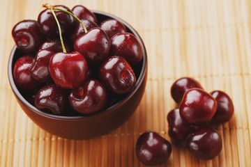 Ripe and juicy cherry berries on a wooden background in a brown cup