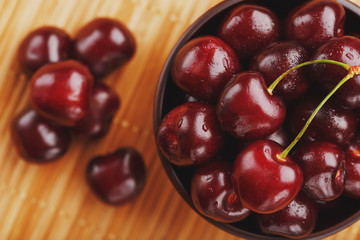 Ripe and juicy cherry berries on a wooden background in a brown cup