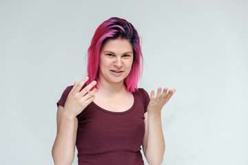Fototapeta na wymiar Portrait to the waist of a young pretty girl teenager in a burgundy T-shirt with beautiful purple hair on a white background in the studio. Talking, smiling, showing hands with emotions.