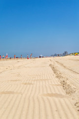 Sable chaud, vue ensoleillée sur les vacanciers à l'horizon.
