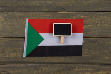 Flag of Sudan and blank blackboard on wooden background