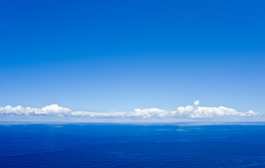 Ruhiges Meer, weiße Wolken und der Blick geht über den Horizont hinaus