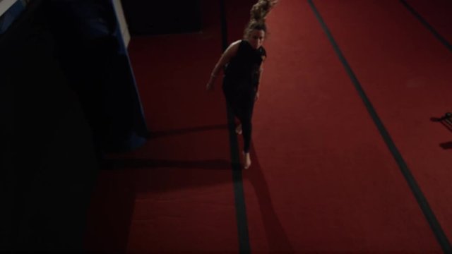 Female athlete doing impressive tumbling on trampolines and gym parcour equipment