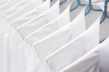 White shirts hanging on rack in a row