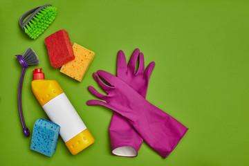 Detergents and cleaning accessories on a green background. Housekeeping concept.