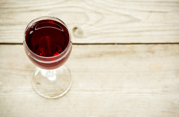 Glass of red wine on wooden table top view
