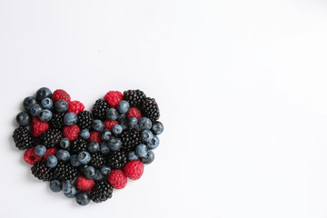 Heart laid out of berries on white background, top view
