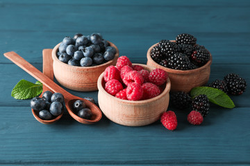 Small wooden bowls with berries on wooden table, space for text