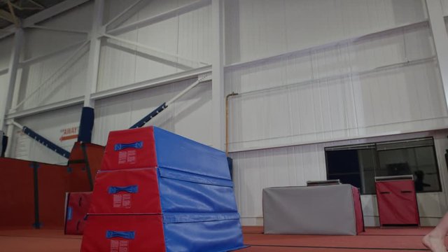 Man training in parcour in the gym with padded equipment and obstacles