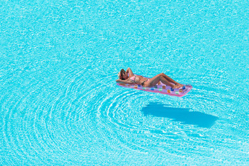 Young woman in bikini air mattress in the big swimming pool