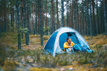young beautiful woman with a tent in the forest, camping, solo travel, nature concept